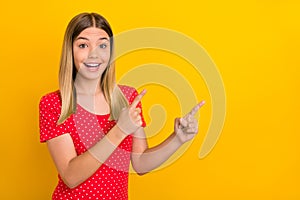 Portrait of surprised funny girl indicate two fingers empty space promo isolated on yellow color background