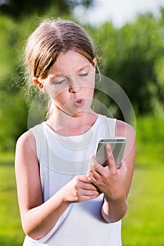 Portrait of surprised girl looking at mobile phone