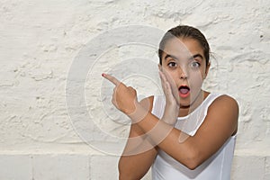 Portrait of a surprised girl pointing her finger at the copy space