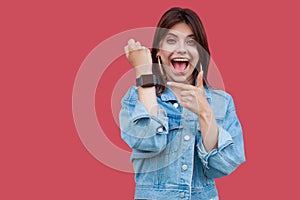 Portrait of surprised happy beautiful brunette young woman in denim casual style standing showing and pointing at screen of her