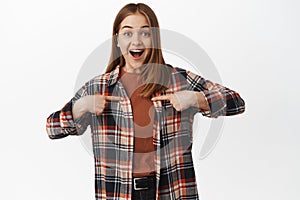 Portrait of surprised and happy young woman gasp amazed, pointing fingers