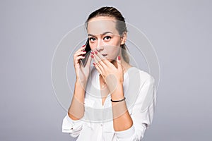 Portrait of surprised and impressed woman with widened eyes and opened mouth, stunned because of something she is hearingin phone