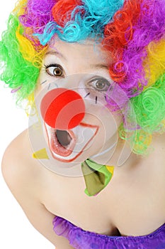 Portrait of a surprised looking female clown with wig and red nose in studio