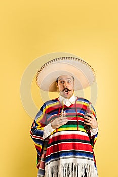 Portrait of surprised man in bright garment isolated over yellow background