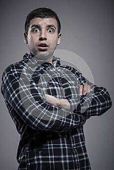 Portrait of surprised man in checked shirt with arms crossed