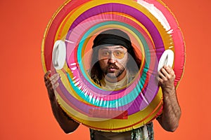 Portrait of a surprised man looking through an inflatable circle close up. Man with colored inflatable circle and