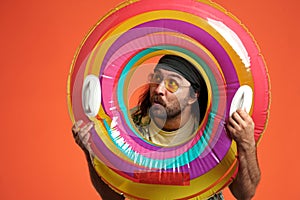 Portrait of a surprised man looking through an inflatable circle close up. Man with colored inflatable circle and