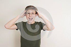 Portrait of surprised teen boy in eyeglasses on white background. Funny boy looking at camera in shock or amazement. Handsome