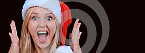 Portrait of surprised woman with her mouth open in a santa hat staring at camera isolated against a dark background