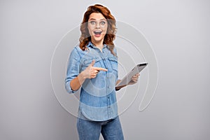 Portrait of surprised woman use tablet search social networking news impressed scream wow omg point index finger wear