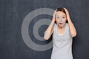 Portrait of surprised woman with widened eyes, holding hands on head