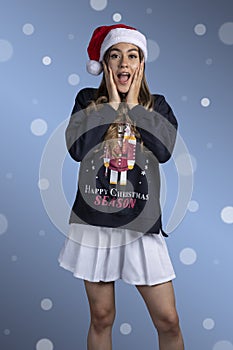 Portrait of surprised young Latin woman with Christmas sweater and Santa Claus hat