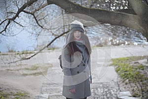 Portrait of surprised young woman in grey autumn coat and hat looking at camera. Beautiful brunette girl with grey eyes