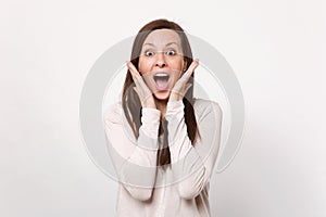 Portrait of surprised young woman in light clothes keeping mouth open, holding hands near face isolated on white