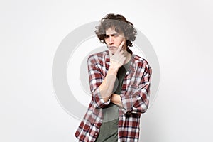 Portrait of suspecting pensive young man in casual clothes looking camera, put hand prop up on chin isolated on white
