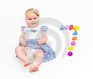 Portrait of a sweet infant baby girl wearing a pink dress and headband bow, isolated on white in studio with number