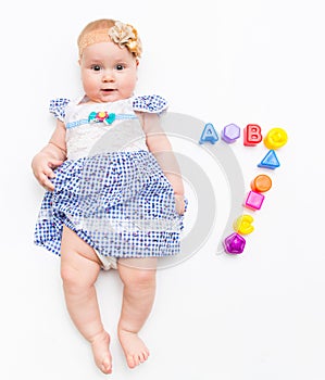 Portrait of a sweet infant baby girl wearing a pink dress and headband bow, isolated on white in studio with number