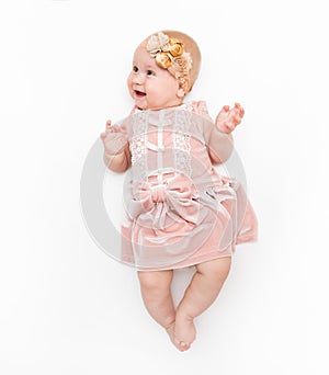 Portrait of a sweet infant wearing a pink dress, headband bow, isolated on white in studio.