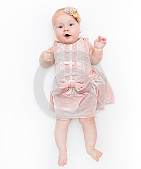 Portrait of a sweet infant wearing a pink dress, headband bow, isolated on white in studio.