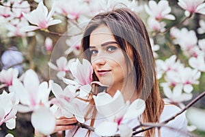 Portrait of sweet lovely young girl in Magnolia blossoming flowers