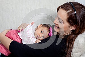 Portrait of a sweet one month baby girl with her young mother at home. Motherhood concept. Family love concept