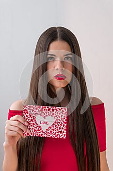 Portrait of a sweet perfect girl smiling at camera with heart shaped paper in her hands. Valentine`s Day or Women`s Day