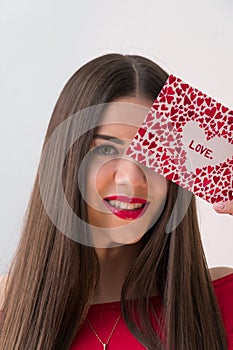 Portrait of a sweet perfect girl smiling at camera with heart shaped paper in her hands. Valentine`s Day or Women`s Day