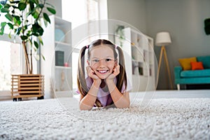 Portrait of sweet positive girl laying comfy carpet floor arms touch cheeks weekend atmosphere flat inside