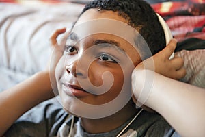 A Portrait of a sweet young boy listening to music on headphones