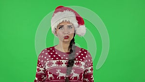 Portrait of sweety girl in Santa Claus hat angrily pointing herself, saying who me no thanks i do not need. Green screen