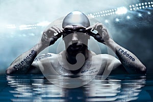 Portrait of a swimmer on the background of a sports arena. The concept of swimming and water games. Front view