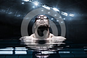 Portrait of a swimmer on the background of a sports arena. The concept of swimming and water games. Front view