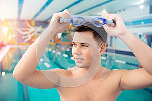 Portrait swimmer happy young man, background swimming pool blue water