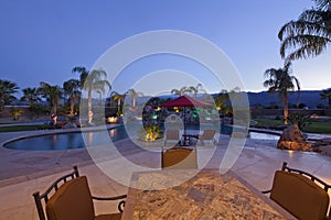 Swimming pool with chaise lounge outside mansion at dusk