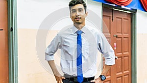 A portrait of a tall young Asian business man wearing a white shirt, blue necktie and hand watch