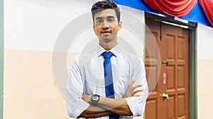 A portrait of a tall young Asian business man wearing a white shirt, blue necktie and hand watch