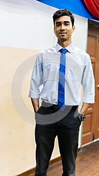 A portrait of a tall young Asian business man wearing a white shirt, blue necktie and hand watch