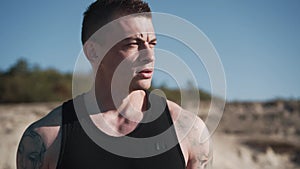 Portrait of tattooed muscular man stands outdoors and looks around