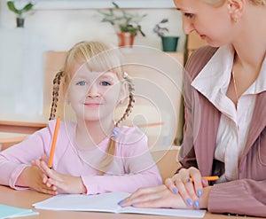 Portrait of a teacher explaining something to a smiling schoolgirl in a classroom