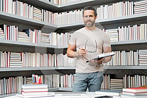 Portrait of teacher in library classroom. Handsome teacher in university library. Teachers Day. Teacher giving classes