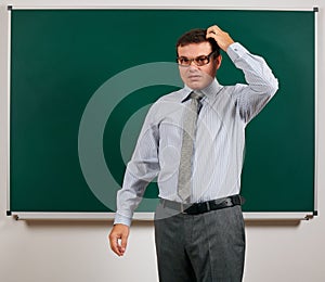 Portrait of a teacher with old fashioned eyeglasses posing at blackboard background - back to school and education concept