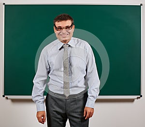 Portrait of a teacher with old fashioned eyeglasses posing at blackboard background - back to school and education concept