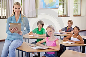 Portrait, teacher and woman with students in classroom, smile and holding folder. Happiness, female educator and group