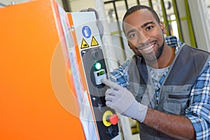 Portrait technician pointing to panel on machine in factory