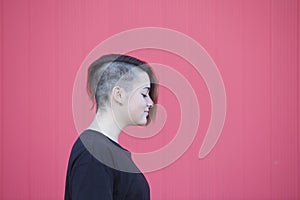 portrait of a teen androgynous lesbian woman on a pink wall