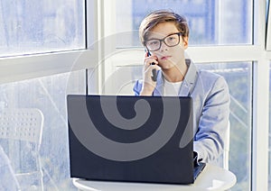 Portrait of teen boy talking over mobile phone and using laptop