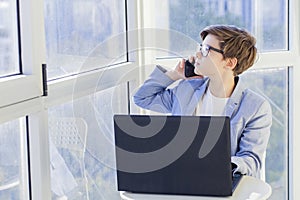 Portrait of teen boy talking over mobile phone and using laptop
