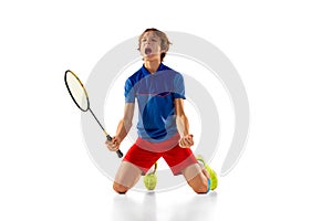 Portrait of teen boy in uniform, badminton player isolated over white background. Emotionally posing, winning