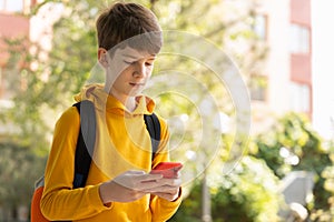 Portrait of teen boy using smartphone. Blogging, surfing, video call. Generation z, mobile generation. Low angle view