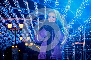 Portrait of teen girl at city skating rink with bright lights in the background in the evening